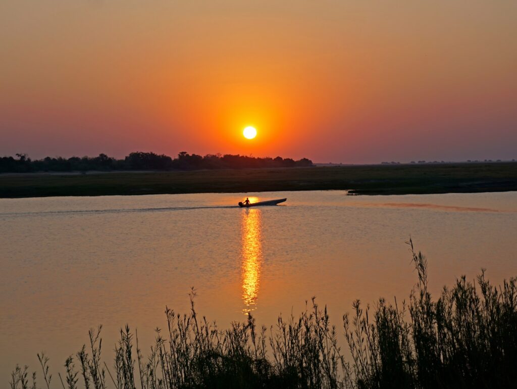 Sunset over the Chobe River with a boat passing by
